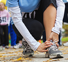 Zoomed in shot of a person&#39;s lower body as they bend down to tie a shoelace before starting a race